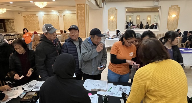 An NYC Votes staff member talks to community members
